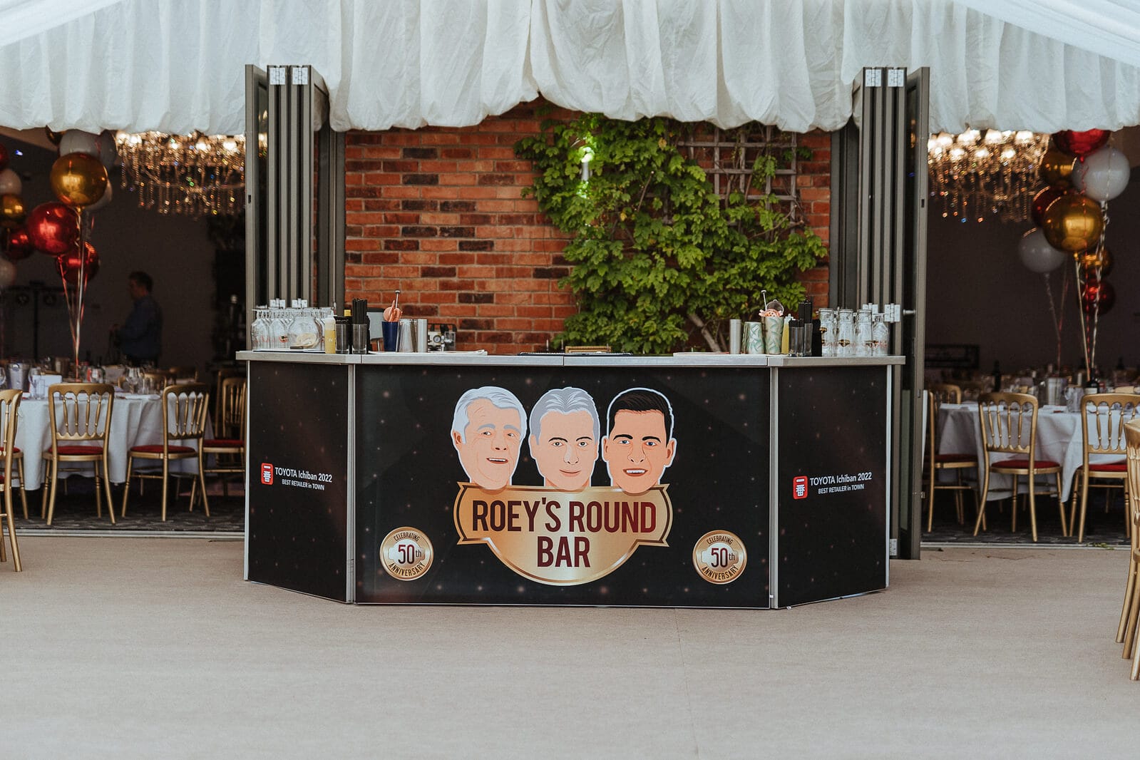 A tent with a sign celebrating Jon Roe Toyota's 50 years in business and winning the Sourcefour Ichiban Award.