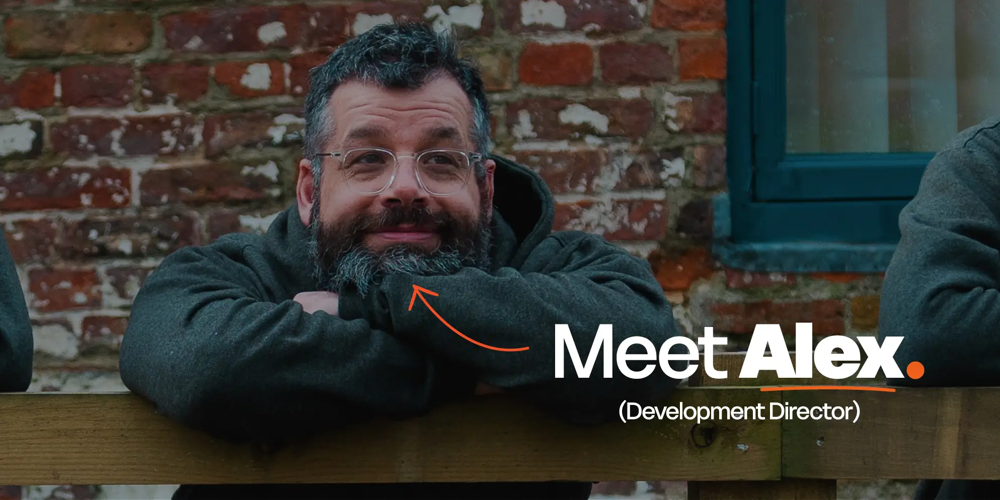 Meet the S4 Team - Sourcefour Development Director Alex leaning on a wooden fence outside of the studio, in front of a brick wall
