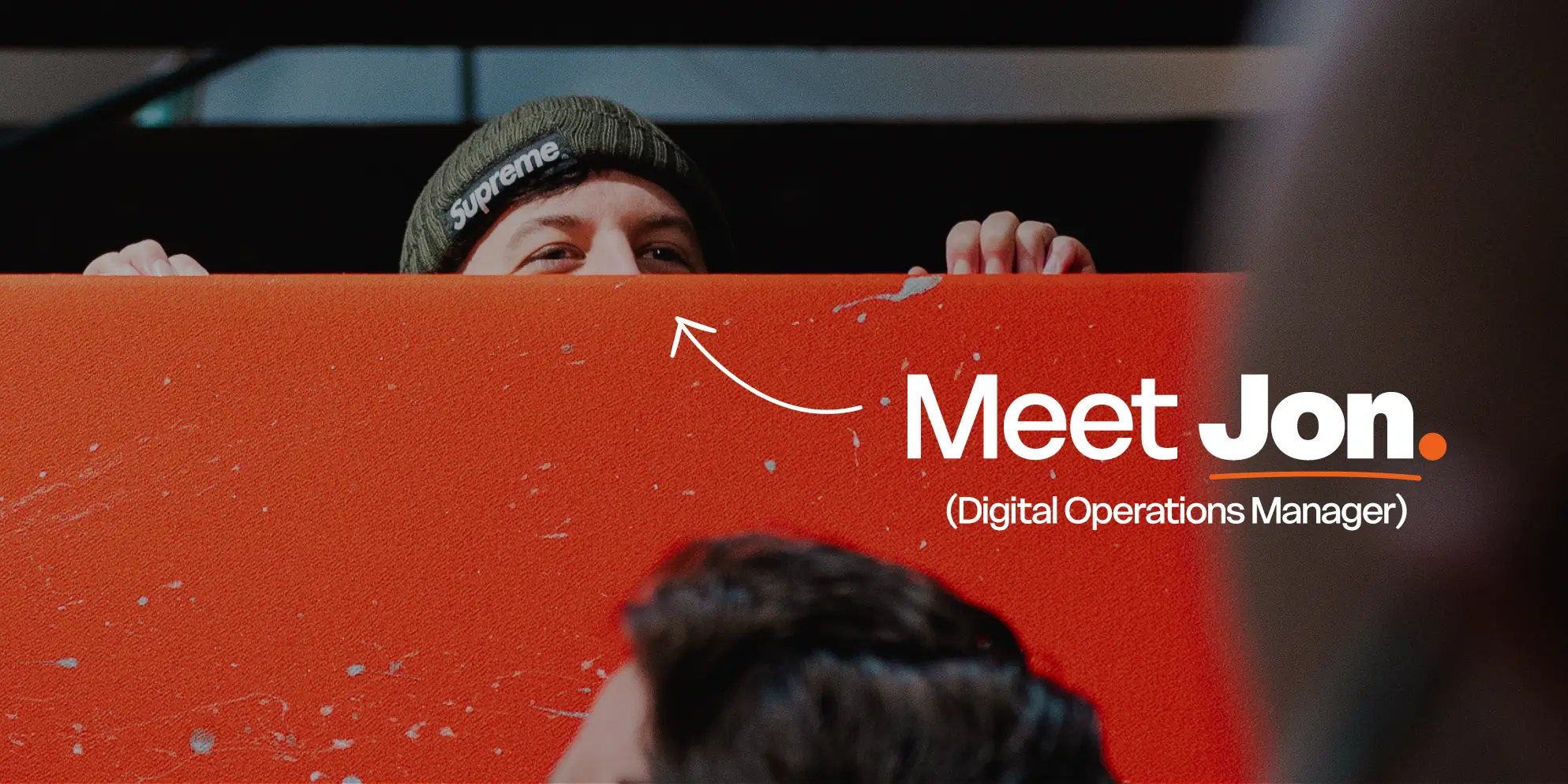 Meet the S4 Team - Sourcefour Digital Operations Manager Jon peeking over an orange room divider in the studio