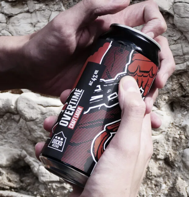 Man opening a can of Docks Beers Overtime Craft Lager designed to show off the artwork created by Sourcefour